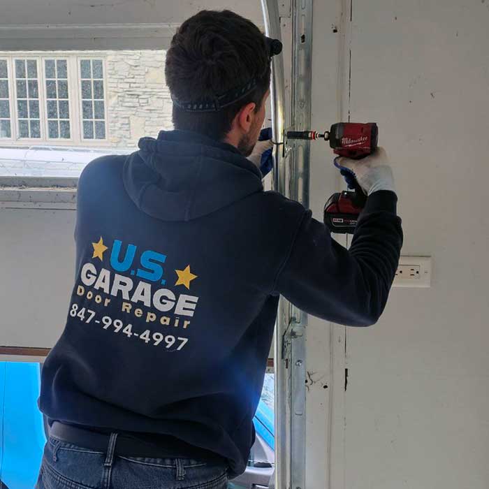 US Garage Door Repair technician fastening a garage door track with a cordless driver
